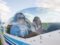 Woman and man pilot looking at camera, showing thumb up, preparing for flying