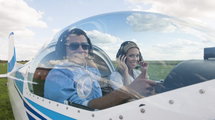 Woman and man pilot looking at camera, showing thumb up, preparing for flying